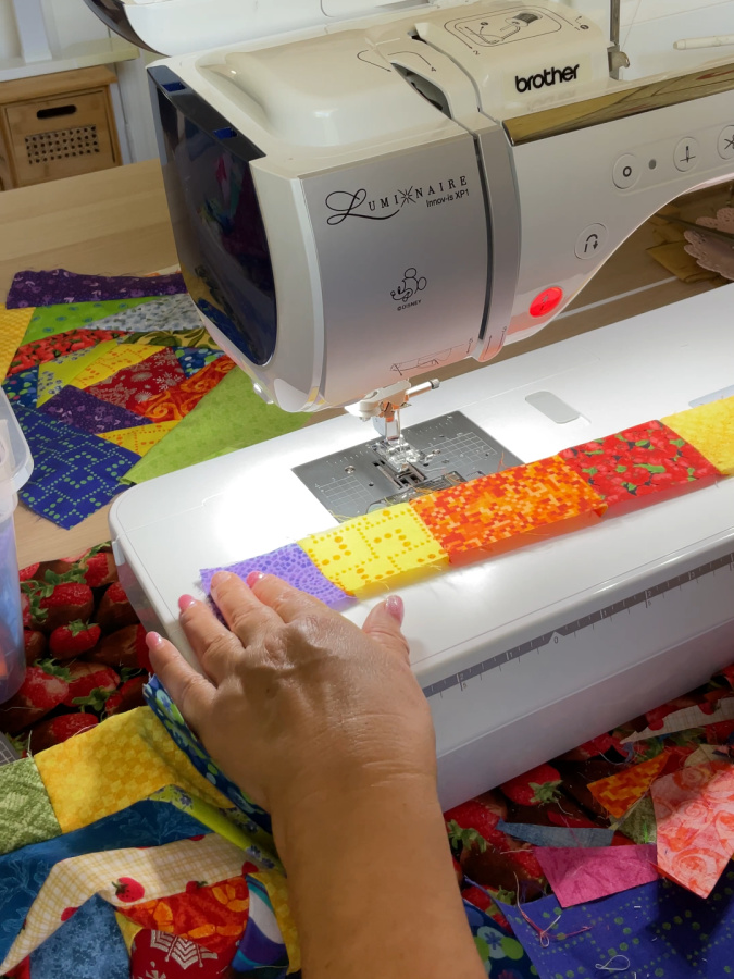 a sewing machine and on it a strip of fabric sewn from crumb pieces of fabric of various colors