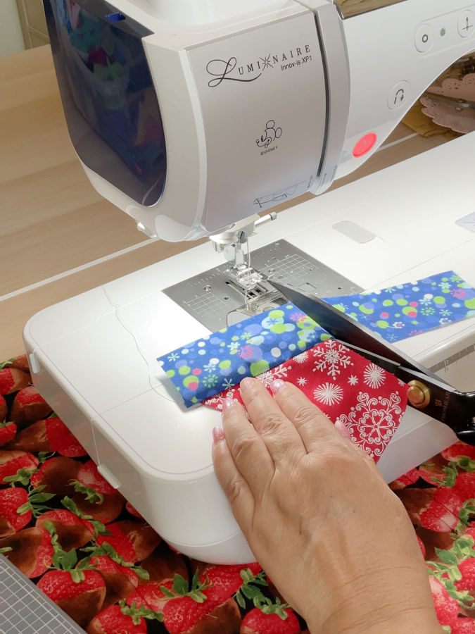 trimming the seam to seam allowance size of a crumb piece of fabric to prepare for the next stitch