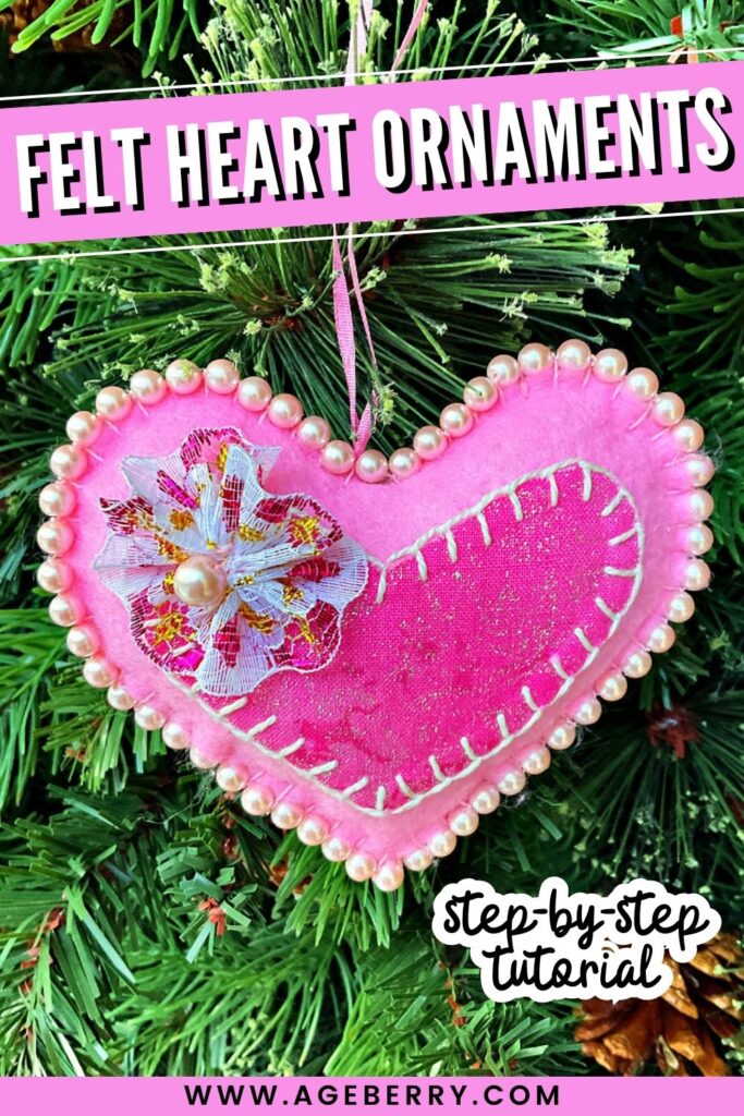 Learn how to sew felt heart ornaments with this beginner-friendly step-by-step tutorial. The image shows a pink felt heart Christmas ornament decorated with pearl beads, hand stitching, and a fabric flower, hanging on a green tree branch as a festive handmade sewing project.