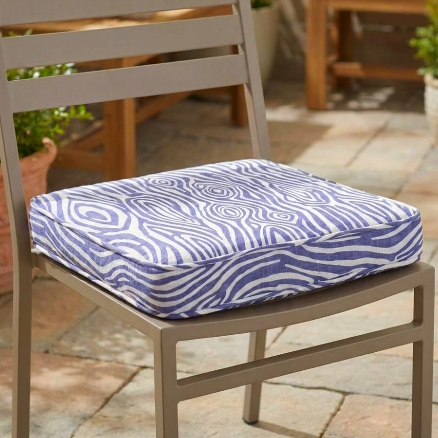a cushion sitting on a simple metallic patio chair the piping on the cushion is visible