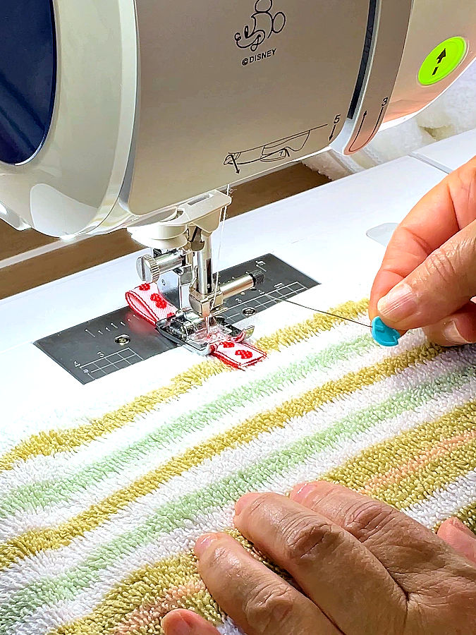 sewing machine needle assembly while sewing the ribbon loop to the towel while the pin was removed and is shown separately