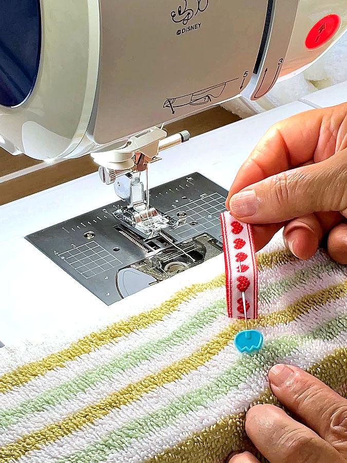 womans hands showing how to pin the piece of ribbon to the towel