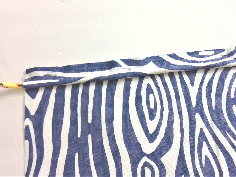 image shows placement of the piping on the material being sewn cord side in, raw edges aligned and pinned in place