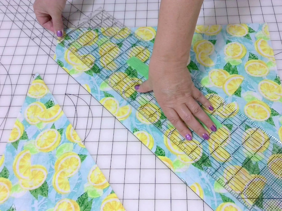 a womans hands shown while arranging a piece of material for a bias cut of a strip of fabric 1.5 inches wide
