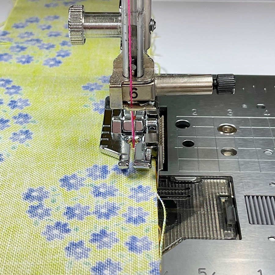 a quarter inch foot with a fabric guide installed in a sewing machine