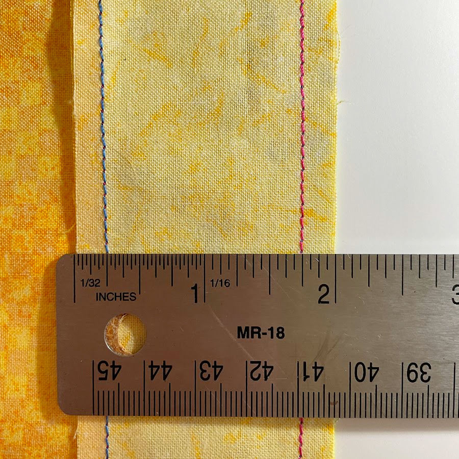 a ruler shown measuring two edge seamd both seams show a quarter inch from the edge of the fabric