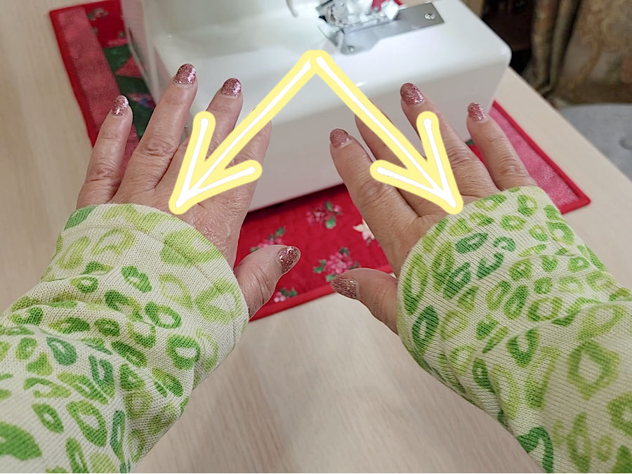 image showing a womans hands showing the too long sleeves the original finish of the sleeves is highlighted with an arrow