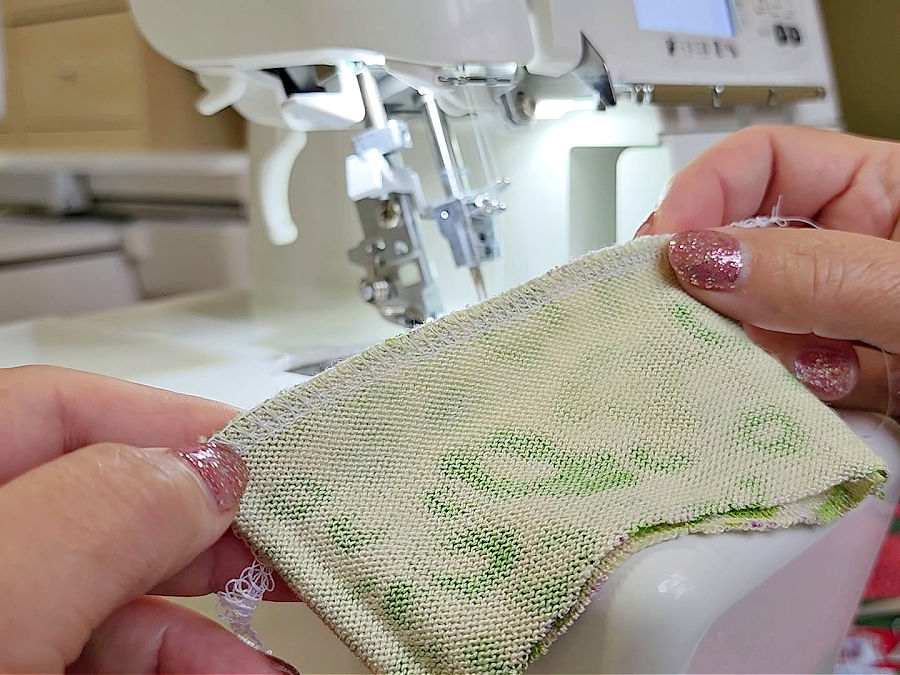 a womans hands shown while she is checking the test seam performed on the scrap piece of material