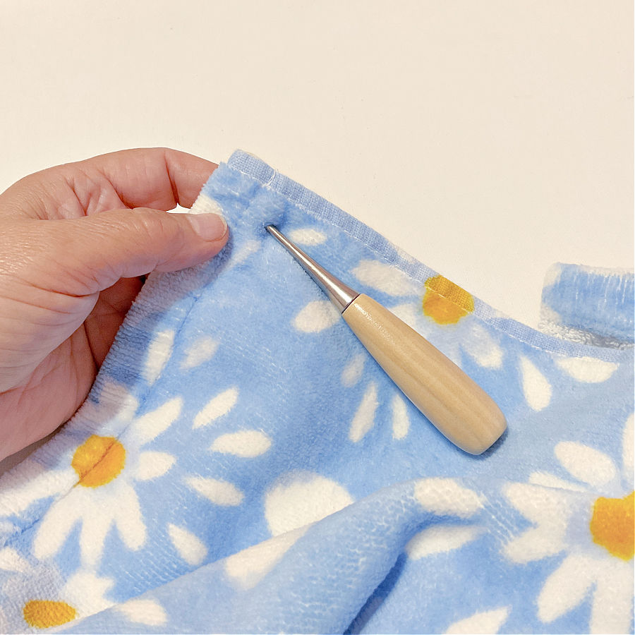 making a hole in the towel to install the snaps the awl is seen already embedded in the towel