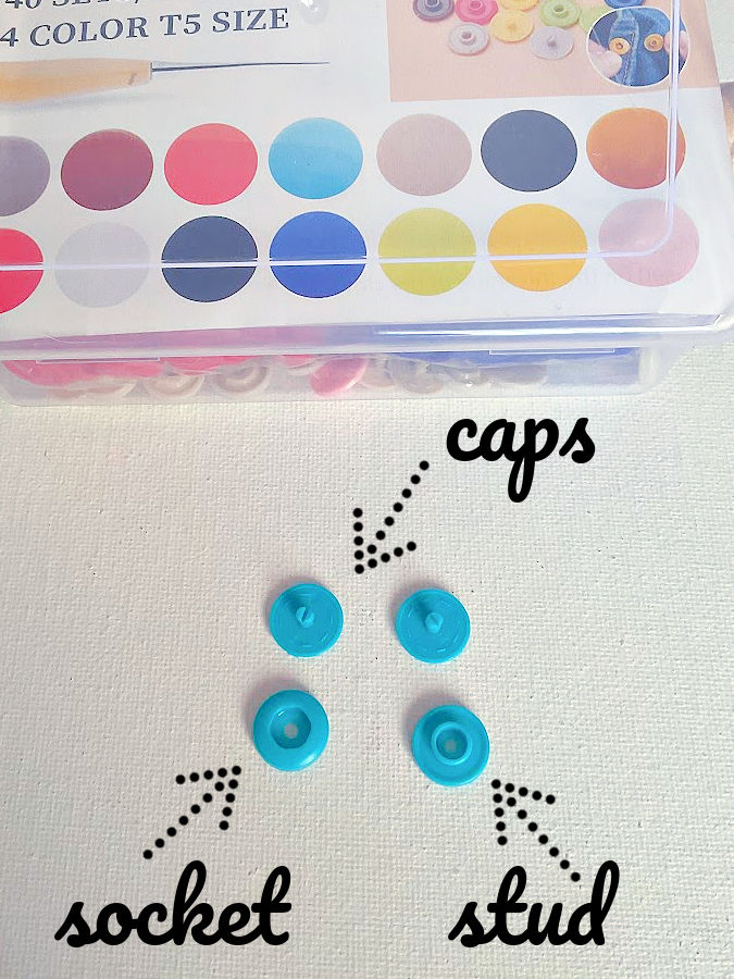 the four pieces that are required to make one snap in the image two caps one socket and one stud the box of snaps visible in the upper part of the image