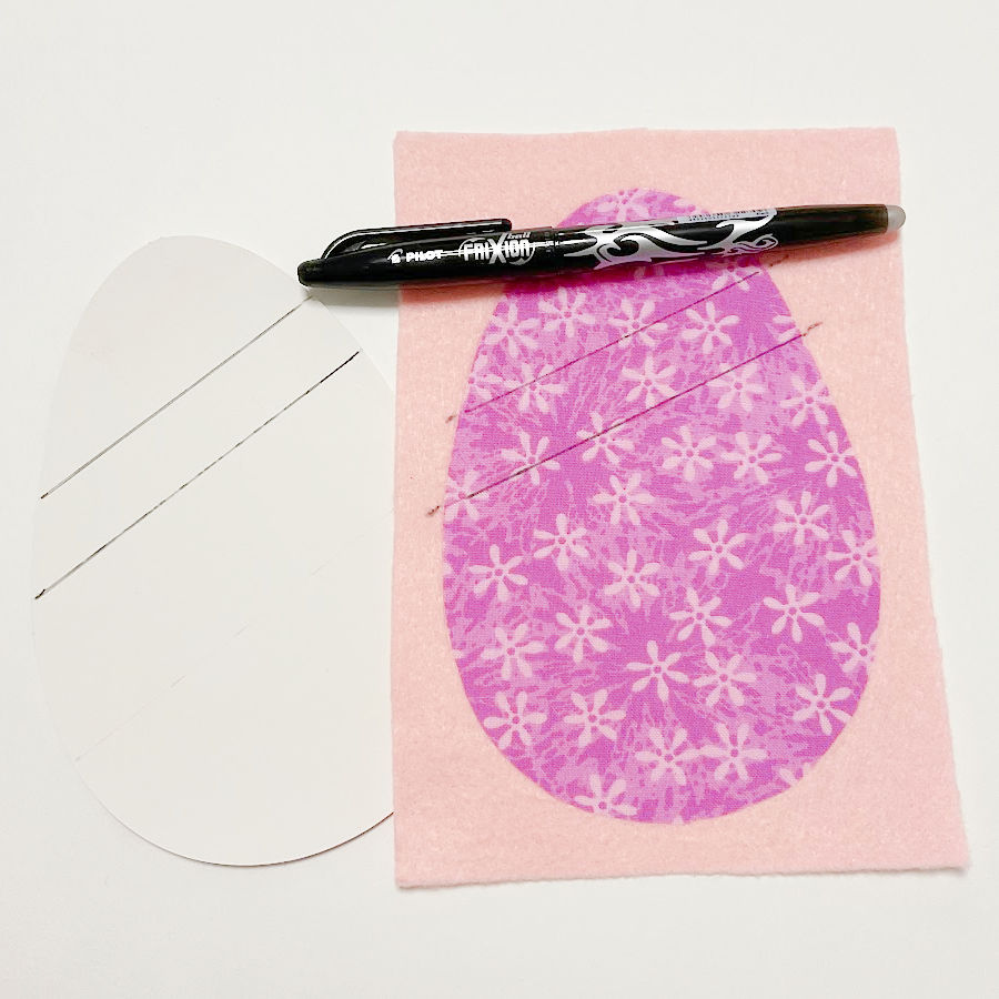 a frixion erasable pen sitting on the face of the easter fabric egg the markings for the decorative ribbon can be seen on the face of the egg