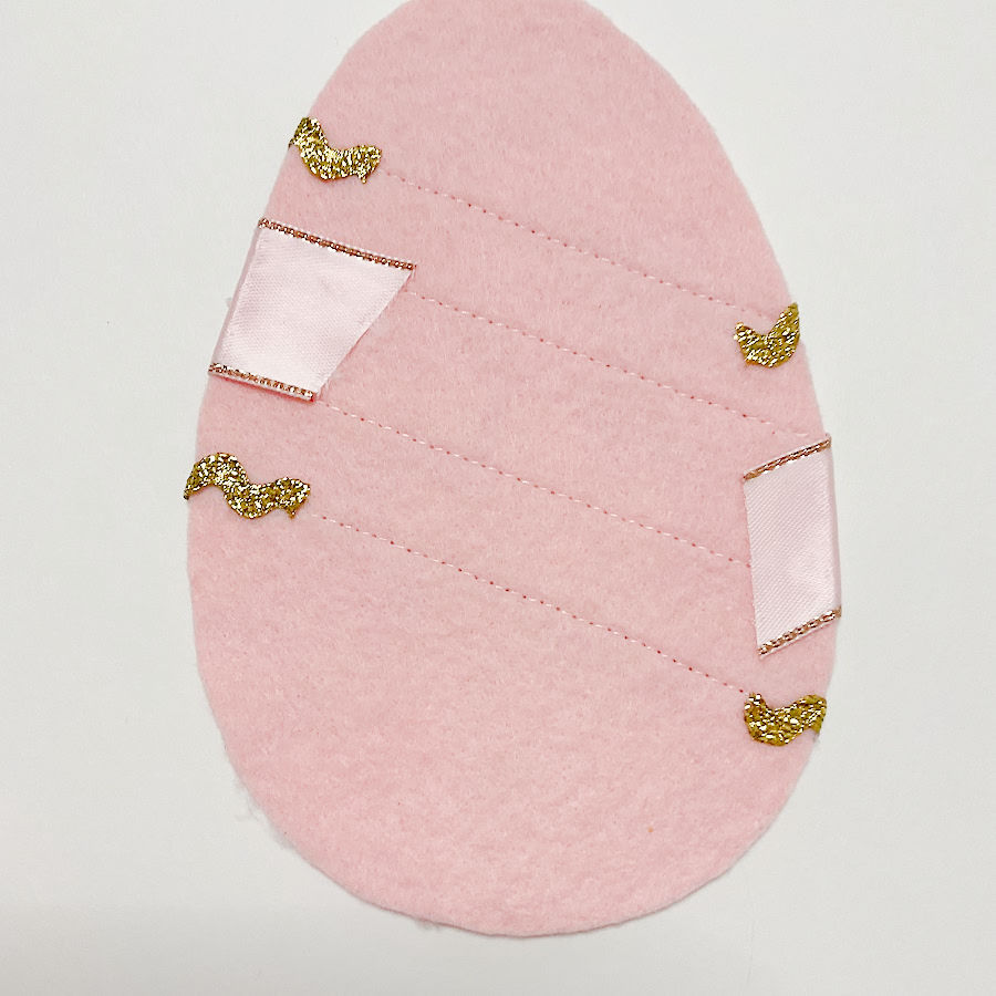 the back of the egg face showing the folded pieces of ribbon secured with fabric glue
