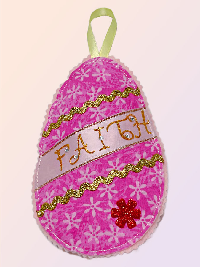 a finished fabric easter egg with the word faith on it and a small decorative flower sticker