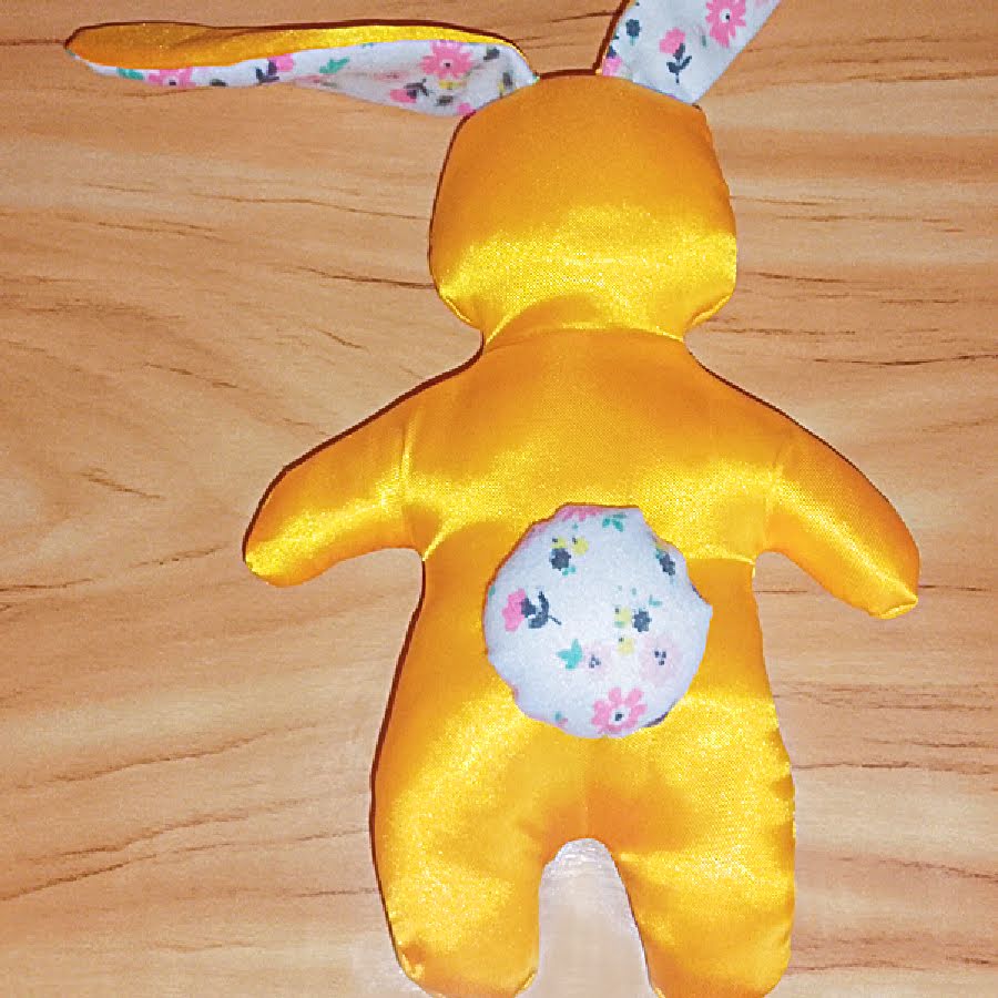 Completed bunny toy viewed from the back, showing the attached round floral tail centered on the lower back.