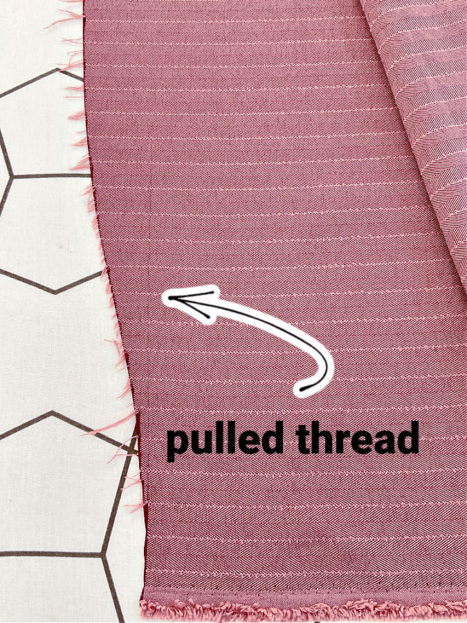 image shows the line of a pulled thread perpendicular on selvage while the fabric is cut in a curved line showing the need to straighten the fabric