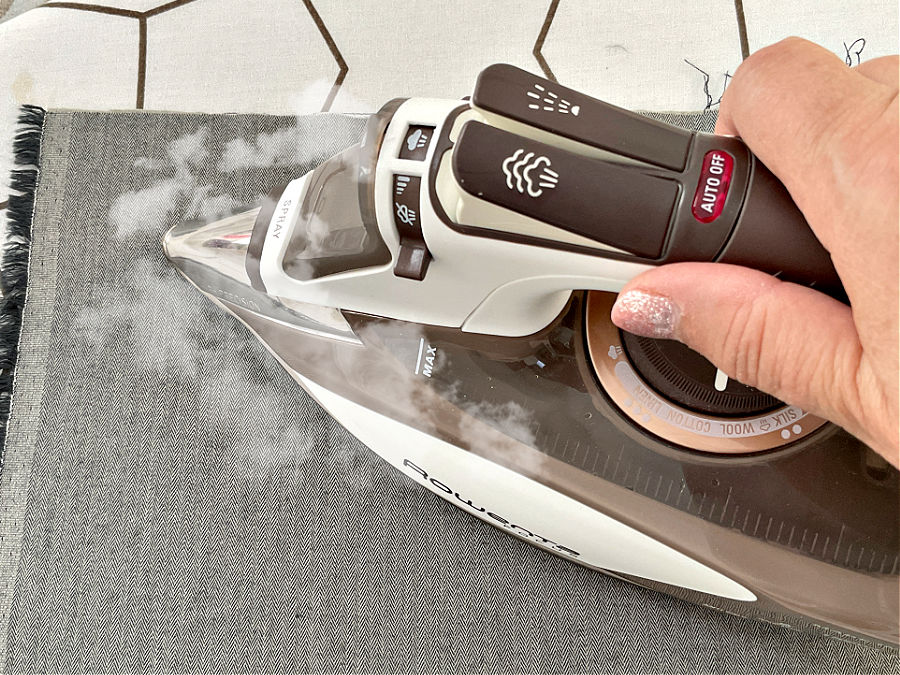 a woman using a steam iron to steam a piece of fabric before using