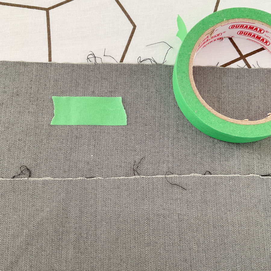 two pieces of the same fabric shown opposing sides of the fabric which seem to be identical and painters tapoe is used to mark one side