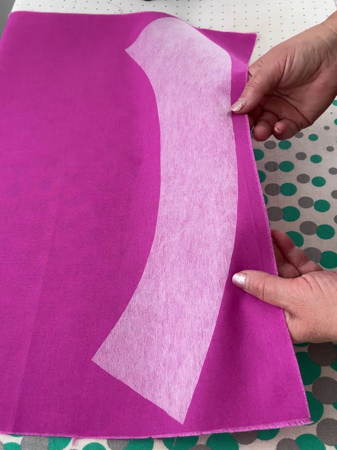 a womans hands shown while holding a piece of fused interfacing for inspection after fusing