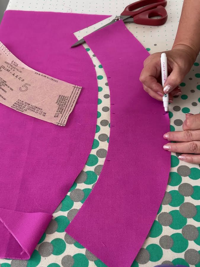 a womand hands marking a piece of fabric using an erasable marker