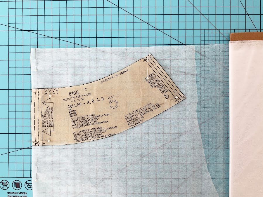 a collar pattern piece arranged on a piece of interfacing prior to cutting