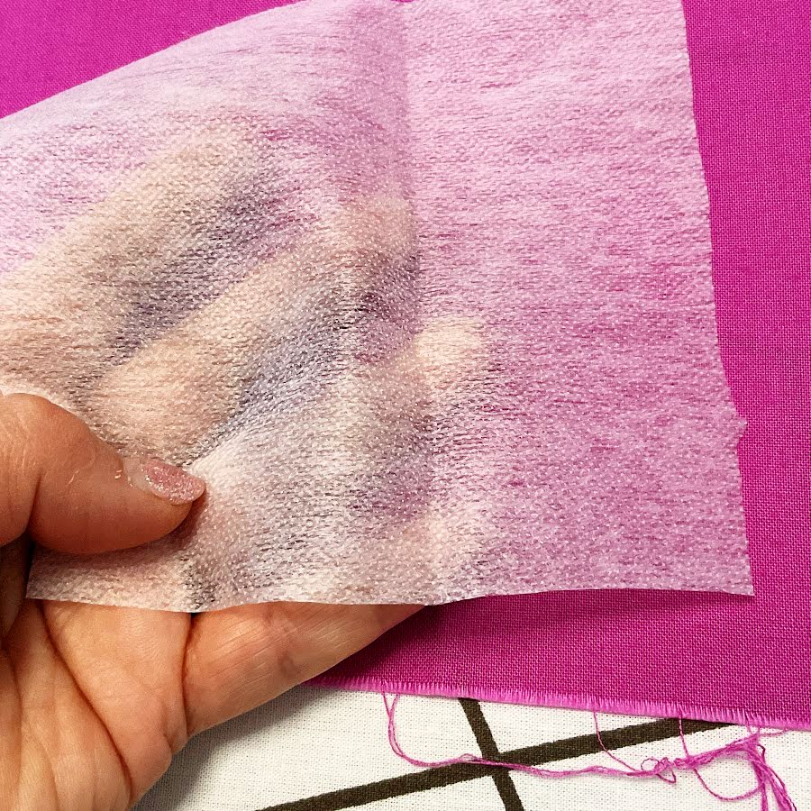 a womans hand shown while touching a piece of interfacing to identify the side with the glue