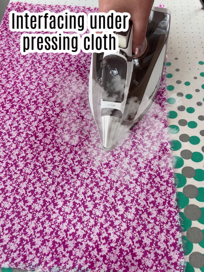 using steam iron with steam showing to fuse interfacing the words interfacing under pressing cloth at the top of the image