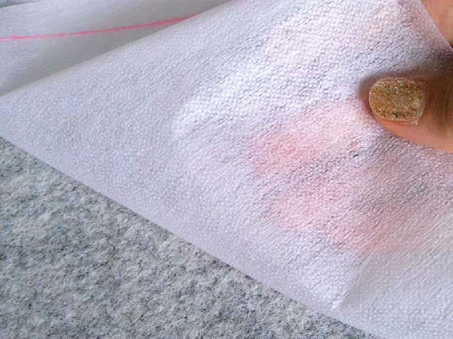 a womans hand holding a piece of interfacing on fabric