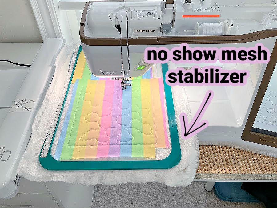 a babylock sewing machine shown while doing embroidery on a piece of fabric using no show mesh stabilizer as backing