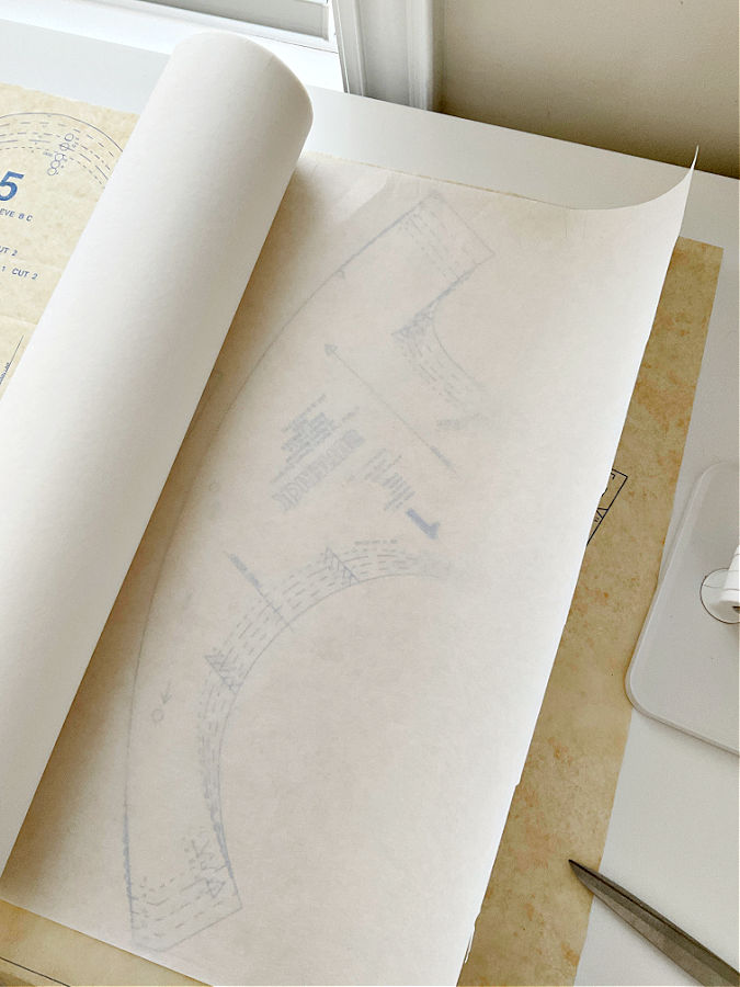 a roll of light embroidery stabilizer sitting on a paper pattern in the pattern is visible under the sheet of stabilizer