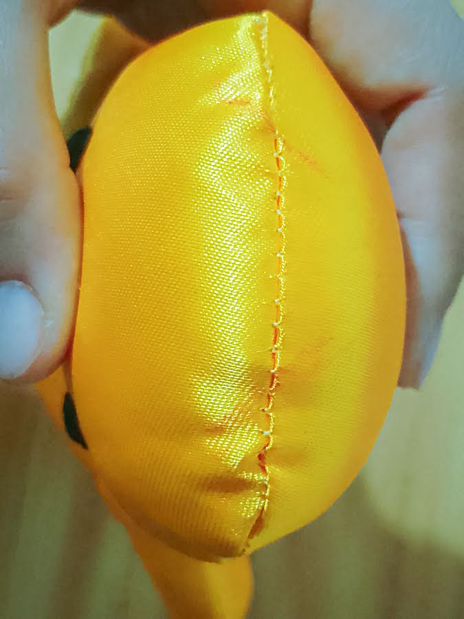 Side view of the stuffed toy head showing the center seam and light placement marks near the top, used as reference points to position the ears evenly on both sides.