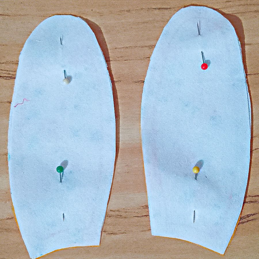 Ear pieces paired right sides together and pinned, with fusible interfacing visible on one layer and pins holding the curved edges aligned.