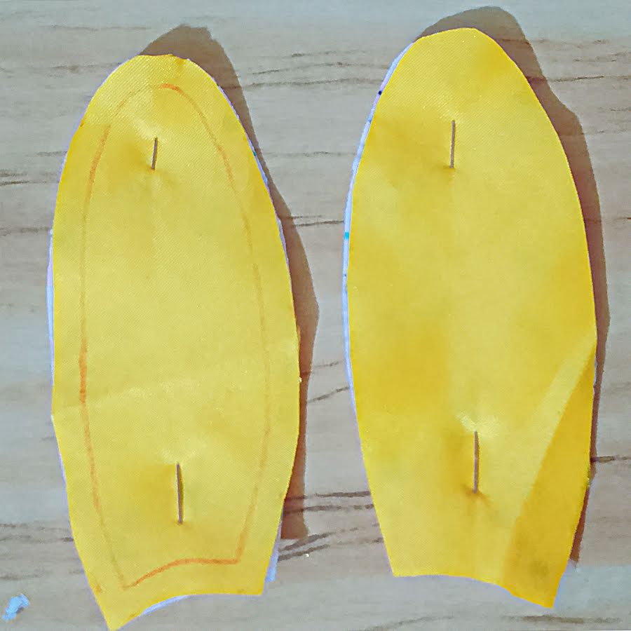 Pinned ear pieces viewed from the fabric side, showing matched edges and the base left open for turning after sewing.