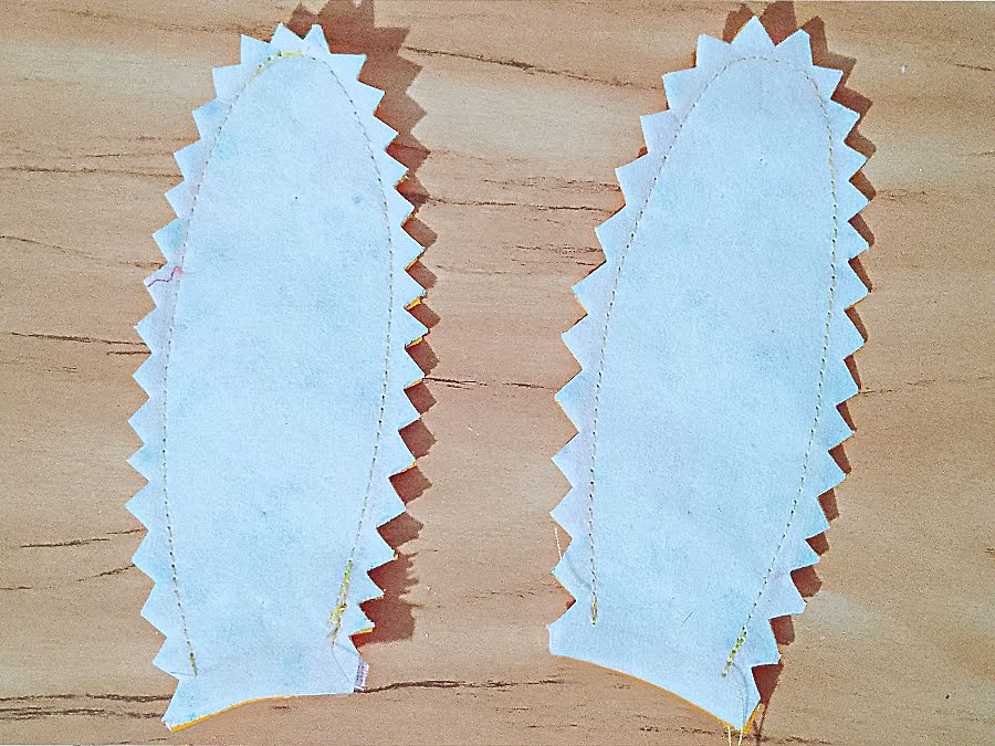 Ear pieces after stitching with seam allowances trimmed using pinking shears, showing zigzag edges around the curves to reduce bulk and help the ears turn smoothly.