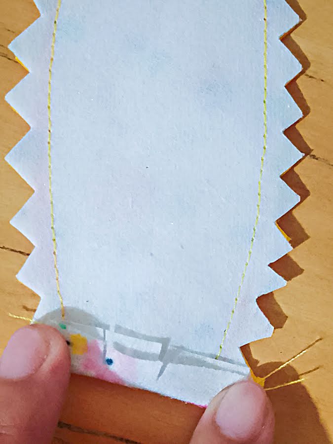 Close-up of the ear base with seam allowances clipped at the curved opening and the raw edges folded inward toward the wrong side, preparing the opening for basting before attaching the ears.