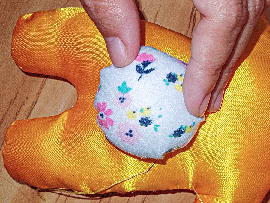 Round tail fabric piece placed on the lower back area of the bunny body to check size and placement before attaching.