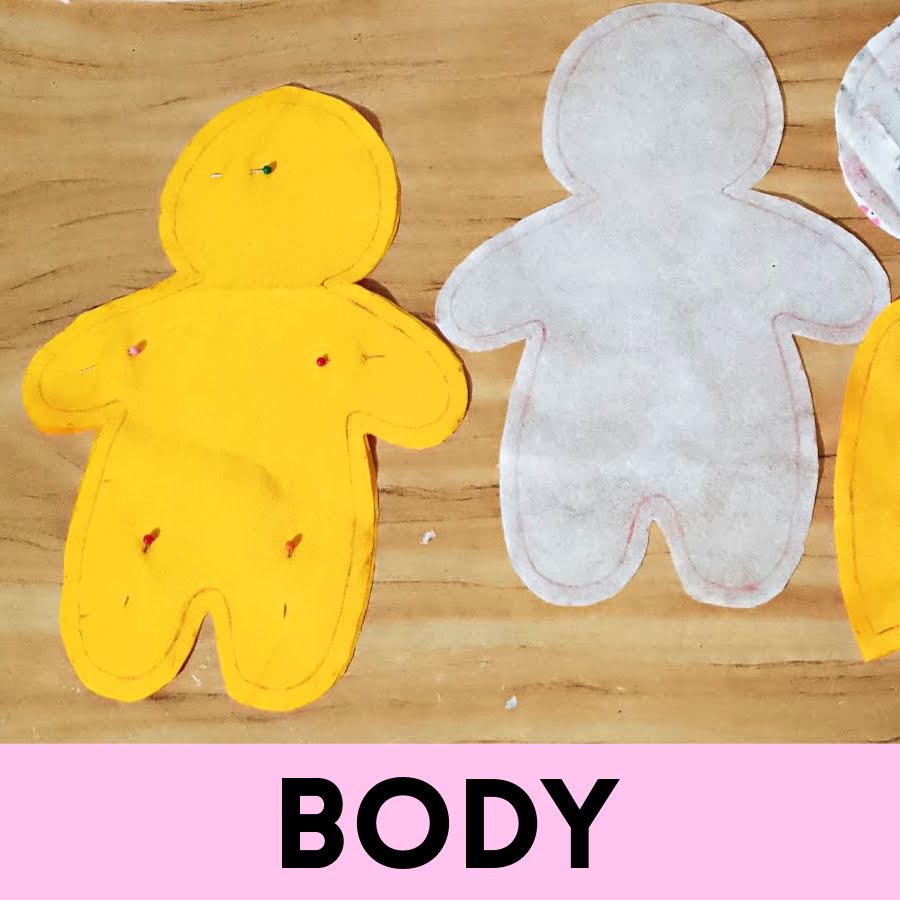 Soft toy body pieces cut from fabric, showing two mirrored body shapes with interfacing attached and pinned in place, seam lines traced and ready for stitching.