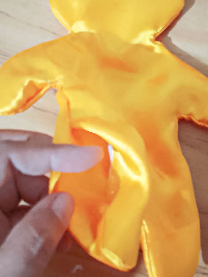 Soft toy body being turned right side out through the opening, showing the fabric pulled through the unsewn section after stitching.