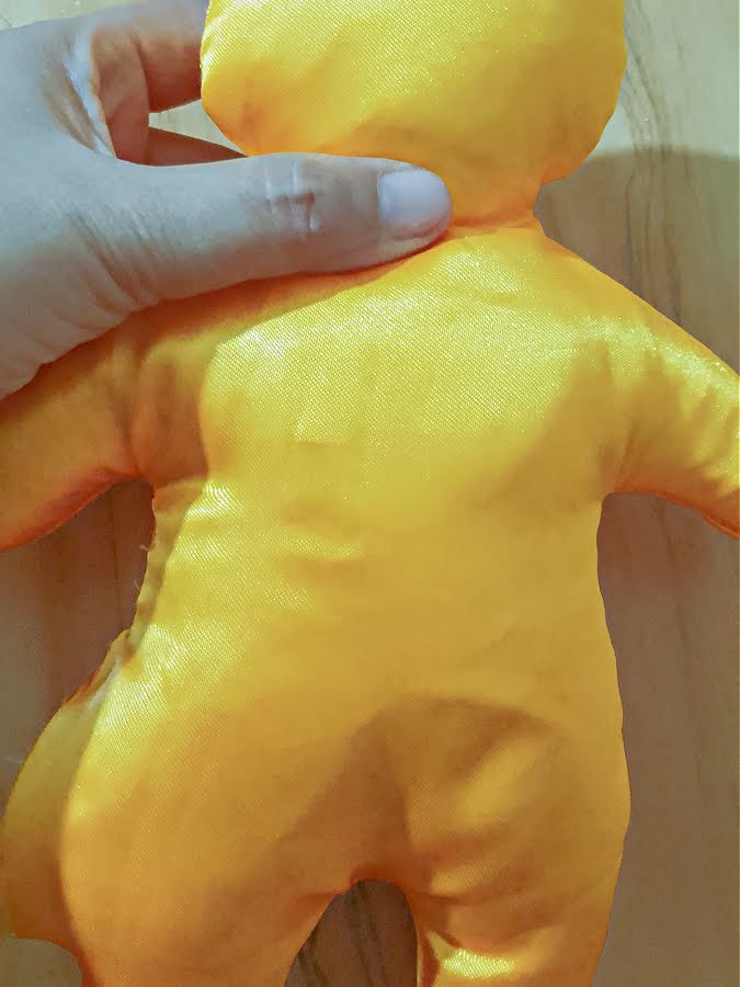 Soft toy body fully stuffed and held upright, showing a smooth, evenly filled shape with defined head, arms, and legs before closing the opening.