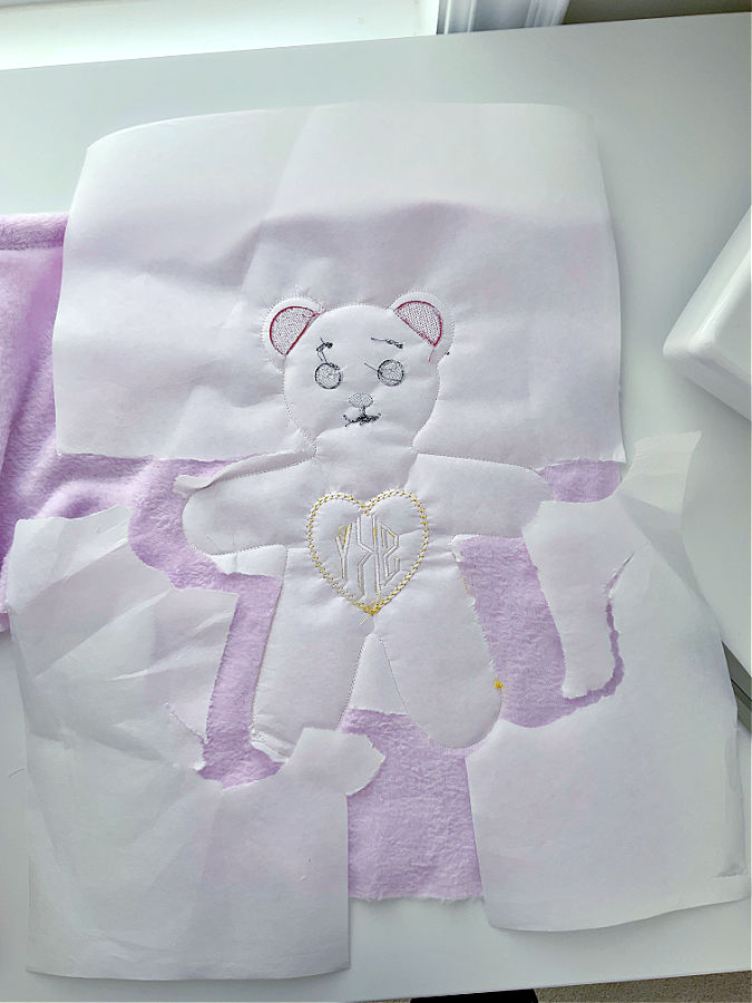 pieces of stabilizer on an embroidery design being torn away when the embroidery is finished