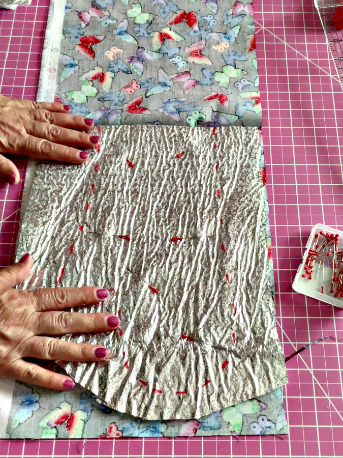 a womans hands smoothing the therm,al bagtting pinned to the other parts of the mitt construction