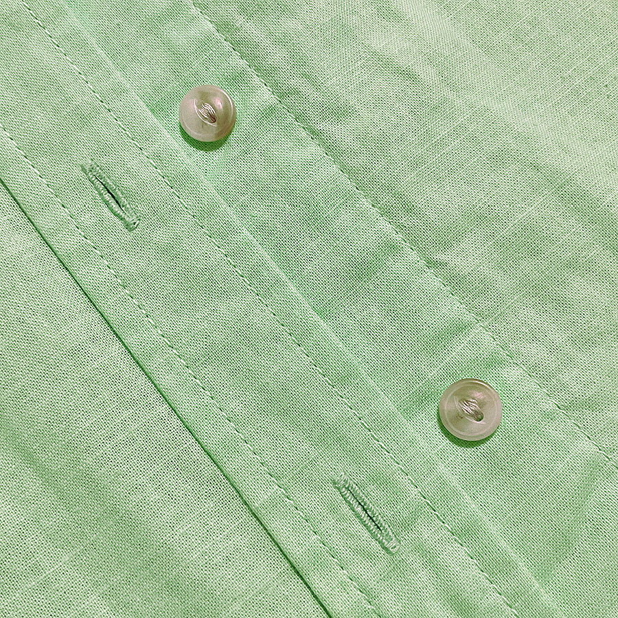 Light green shirt placket with translucent buttons and neatly stitched rectangular buttonholes.