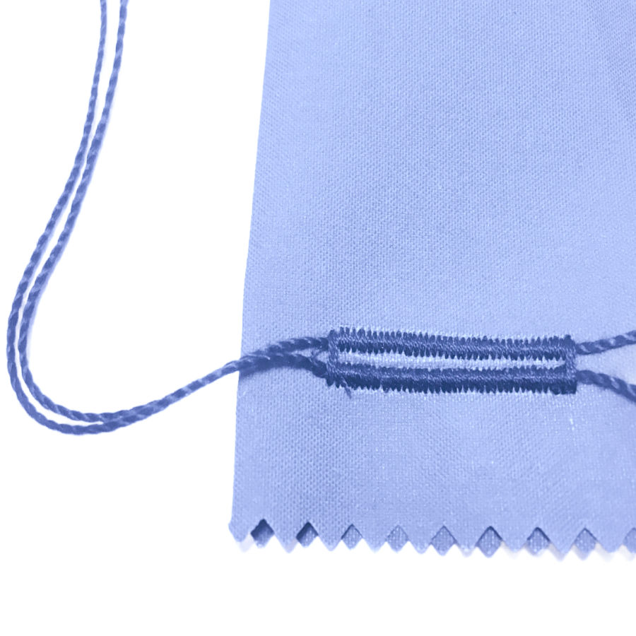 Close-up of a corded buttonhole sample on pale blue fabric, with the reinforcing cord visible at both ends.