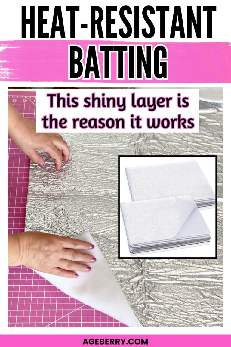 Hands lifting a piece of heat resistant batting with a shiny reflective layer on a pink cutting mat, showing the silver side and white backing