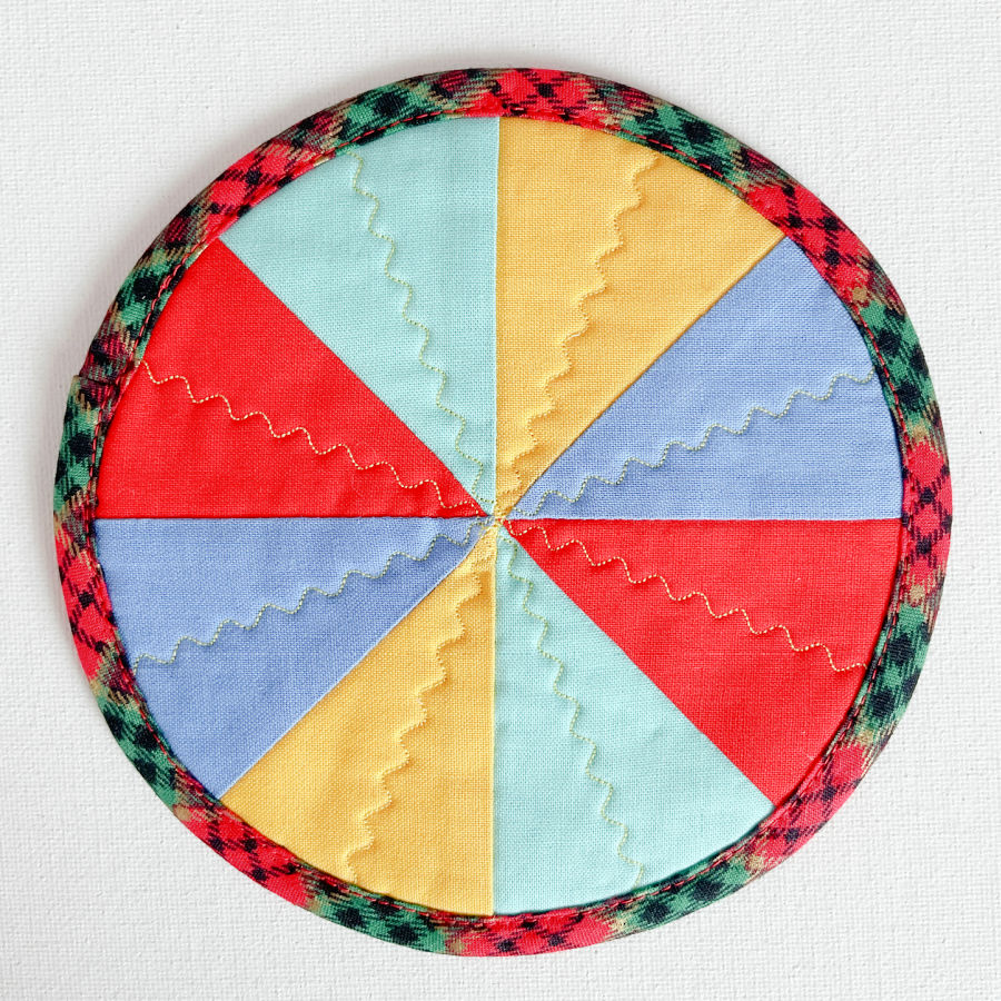 the front of the jar opener showing the pinwheel like fabric assembly and the decorative stitching
