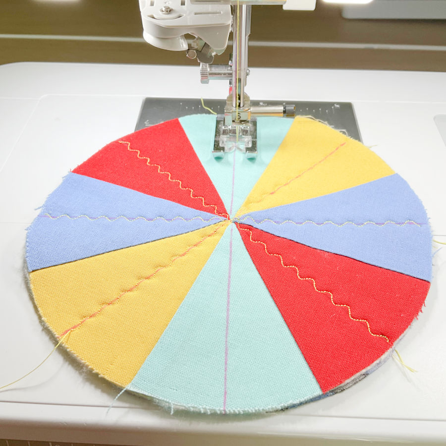the sewing machine while sewing a serpentine decorative stitch following the guide lines through the center of the color sections