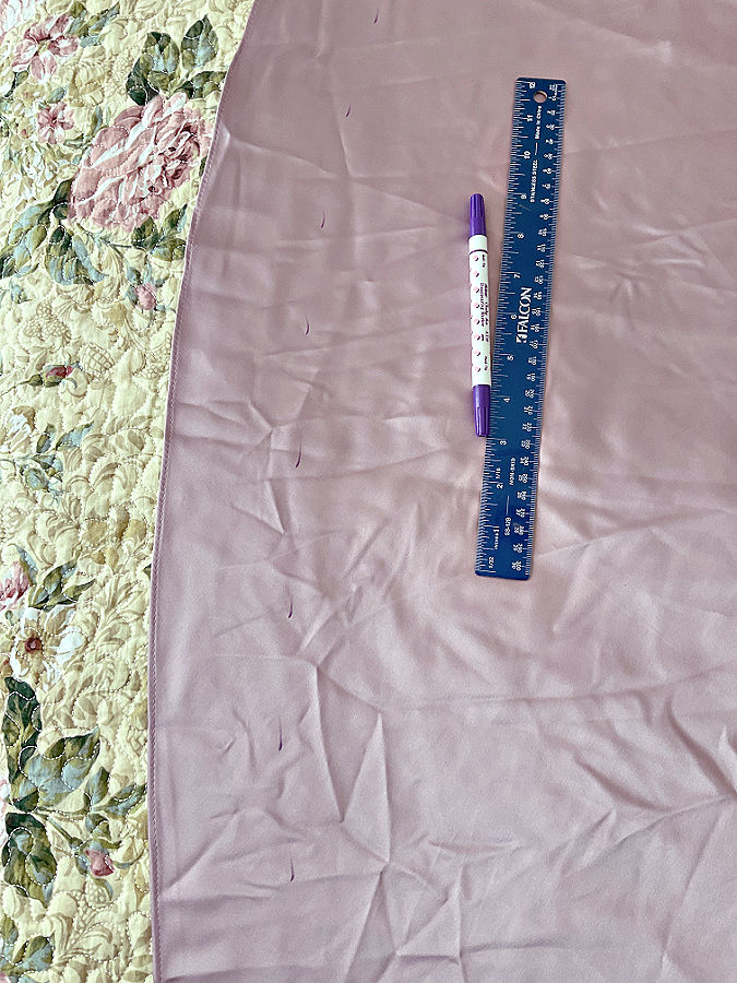 the dress to be hemmed lying flat on a bed the markings for the cutting line shown drawn with erasable pen