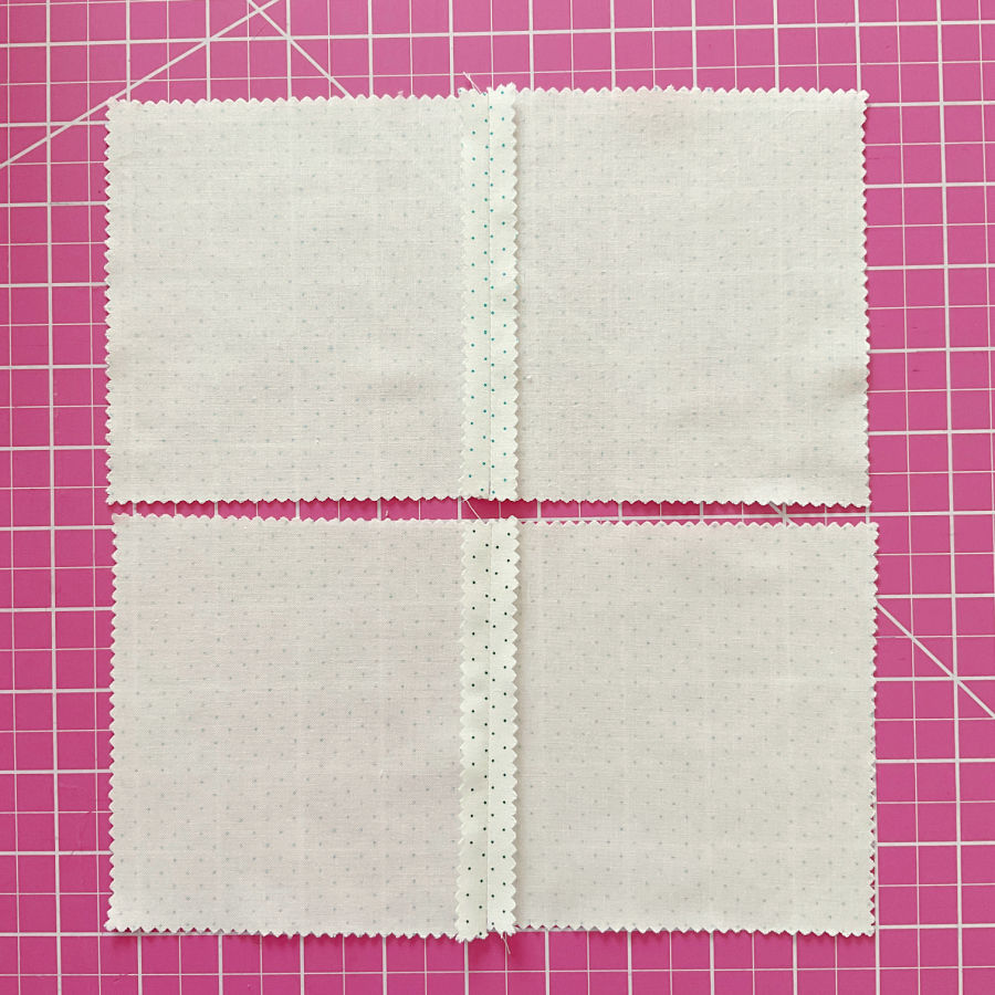 two pieces of white material with colored dots waiting to be pattern matched and sewn together