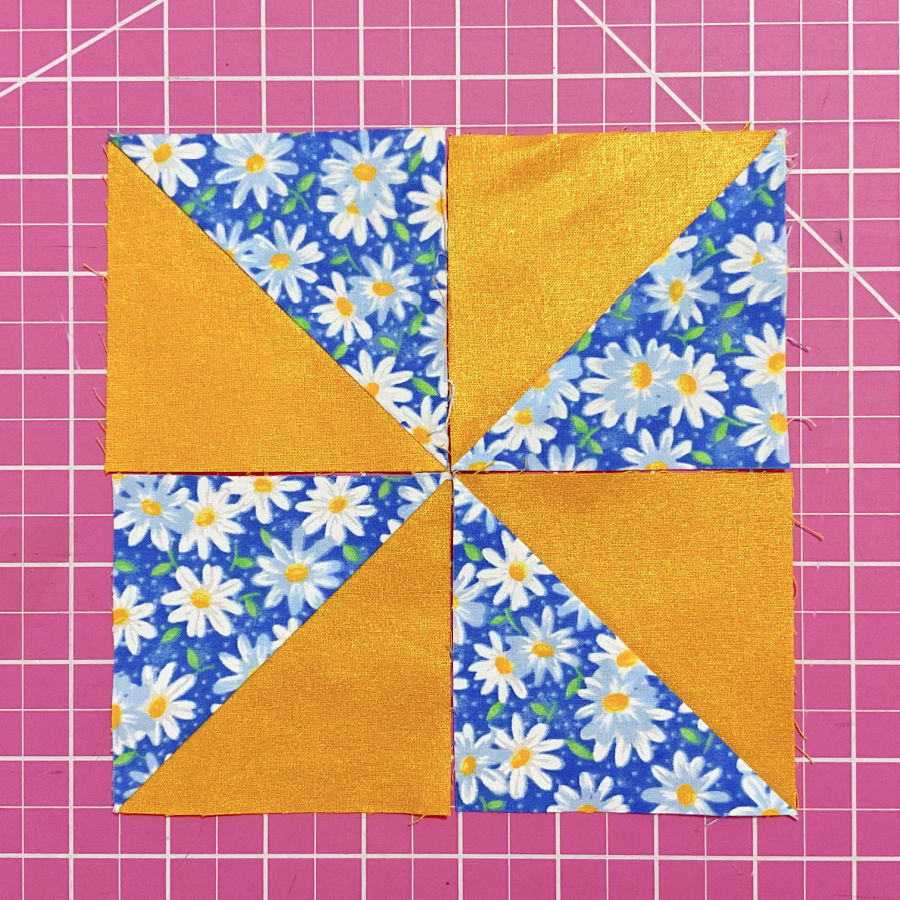 a quilt block composed of four half square triangles in white/blue and orange colors