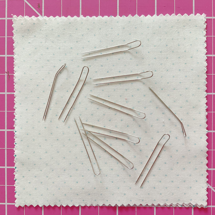 a number of fork pins arranged on a square piece of fabric sitting on a cutting table