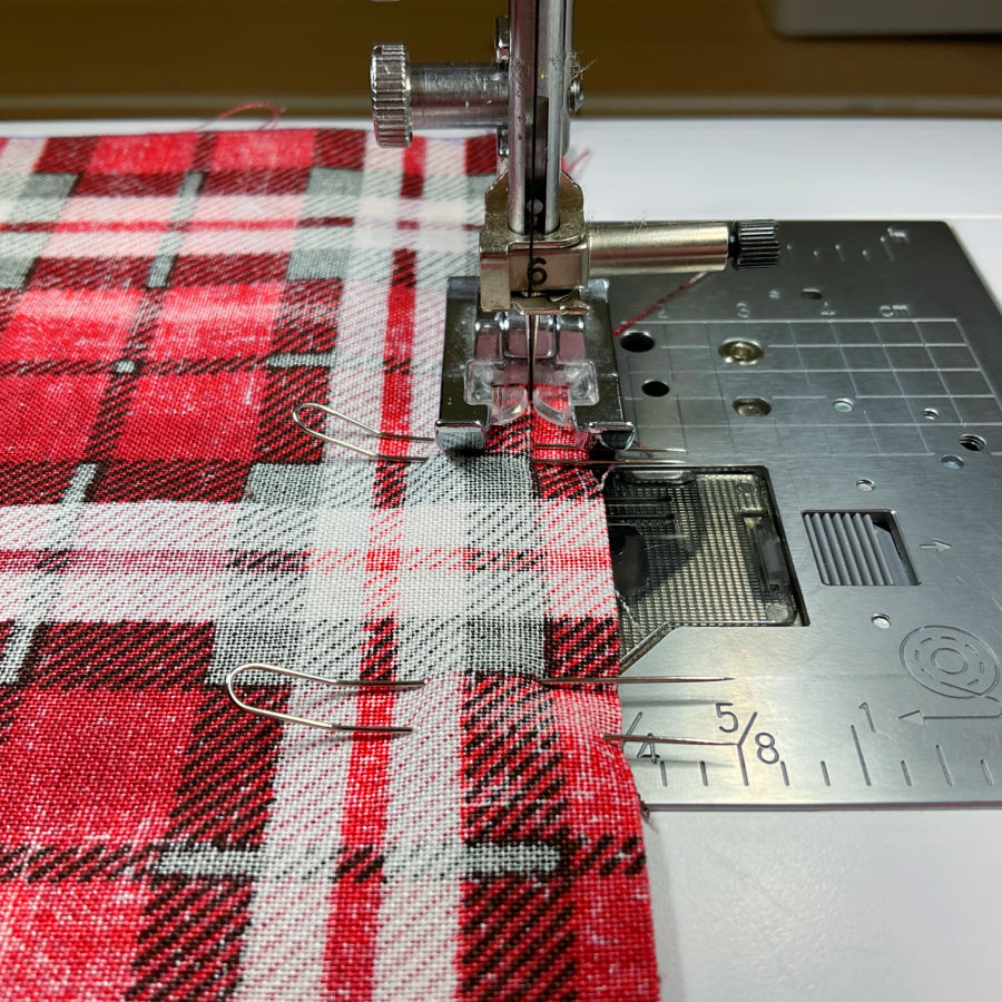 a sewing machine needle assembly shown while sewing a seam where fork pins are involved